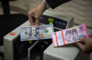 Seorang petugas menunjukan pecahan Dolar AS dan Rupiah di salah satu tempat penukaran mata uang asing di Kwitang, Jakarta, Senin (9/12/2024). Foto: Iqbal Firdaus/kumparan
