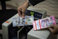Seorang petugas menunjukan pecahan Dolar AS dan Rupiah di salah satu tempat penukaran mata uang asing di Kwitang, Jakarta, Senin (9/12/2024). Foto: Iqbal Firdaus/kumparan
