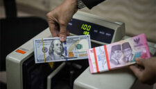 Seorang petugas menunjukan pecahan Dolar AS dan Rupiah di salah satu tempat penukaran mata uang asing di Kwitang, Jakarta, Senin (9/12/2024). Foto: Iqbal Firdaus/kumparan
