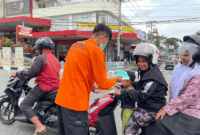 Petugas BPBD Padang Panjang membagikan masker kepada pengendara sepeda motor, pasca erupsi Gunung Marapi.