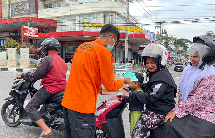 Petugas BPBD Padang Panjang membagikan masker kepada pengendara sepeda motor, pasca erupsi Gunung Marapi.