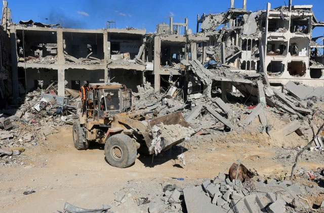 Alat berat membersihkan puing-puing bangunan yang hancur di Kota Gaza, Selasa (14/10/2025). Foto: Ebrahim Hajjaj/REUTERS