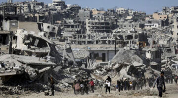 Sejumlah warga berjalan di dekat bangunan yang hancur akibat gencatan senjata Hamas-Israel di Jabalia, Jalur Gaza, Selasa (21/1/2025). Foto: Dawoud Abu Alkas/REUTERS