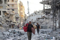 Warga berjalan di tengah kehancuran di Kota Gaza, Jalur Gaza utara, Minggu (12/10/2025). Foto: Ebrahim Hajjaj/REUTERS
