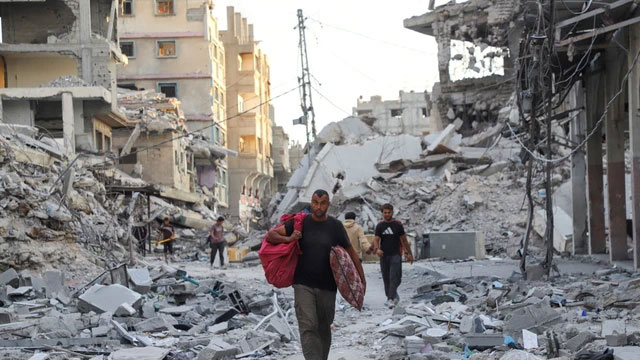 Warga berjalan di tengah kehancuran di Kota Gaza, Jalur Gaza utara, Minggu (12/10/2025). Foto: Ebrahim Hajjaj/REUTERS
