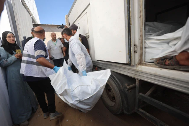 Petugas kamar mayat membongkar jenazah warga Palestina yang sebelumnya berada dalam tahanan Israel, setelah diangkut dengan kendaraan Bulan Sabit Merah dan truk berpendingin, ke Rumah Sakit Nasser di Khan Yunis, Jalur Gaza selatan, Rabu (15/10/2025). Foto: OMAR AL-QATTAA/AFP