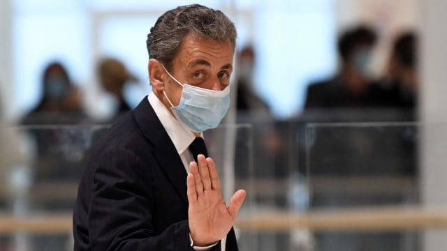 Mantan presiden Prancis Nicolas Sarkozy melambai ketika dia meninggalkan ruang sidang. Foto: Bertrand Guay/AFP