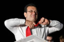 Walikota Istanbul dan kandidat oposisi utama Partai Rakyat Republik (CHP) Ekrem Imamoglu melepas dasinya di depan para pendukung yang merayakan di luar gedung kotamadya utama setelah pemilihan kota di seluruh Turki, di Istanbul (31/3) Foto: Yasin Akgul/AFP

