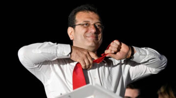 Walikota Istanbul dan kandidat oposisi utama Partai Rakyat Republik (CHP) Ekrem Imamoglu melepas dasinya di depan para pendukung yang merayakan di luar gedung kotamadya utama setelah pemilihan kota di seluruh Turki, di Istanbul (31/3) Foto: Yasin Akgul/AFP
