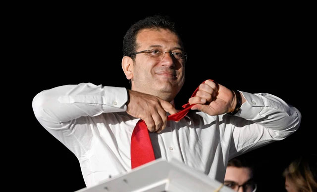Walikota Istanbul dan kandidat oposisi utama Partai Rakyat Republik (CHP) Ekrem Imamoglu melepas dasinya di depan para pendukung yang merayakan di luar gedung kotamadya utama setelah pemilihan kota di seluruh Turki, di Istanbul (31/3) Foto: Yasin Akgul/AFP
