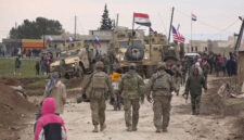 Warga Rusia, Suriah, dan lainnya berkumpul di samping konvoi militer Amerika yang terjebak di desa Khirbet Ammu, sebelah timur kota Qamishli, Suriah, 12 Februari 2020. Foto: AP Photo