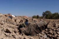 Seorang pria Afghanistan duduk melewati rumah yang rusak pasca gempa baru-baru ini di Afghanistan, Senin (9/10/2023). Foto: Ali Khara/REUTERS
