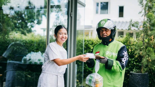 Pemilik Lunch For My Husband (LFMH), Yori Atira memberikan paket sandwich kepada mitra driver GoSend. Foto: Dok. Gojek
